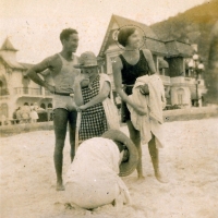 Zélia na praia com casas ao fundo 